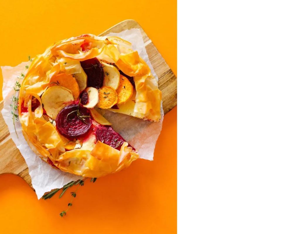 Photo of a savory apple tart with flaky phyllo crust being served on a wooden board.