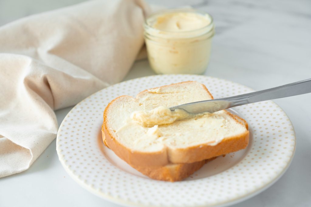 knife spreading vegan butter on white bread