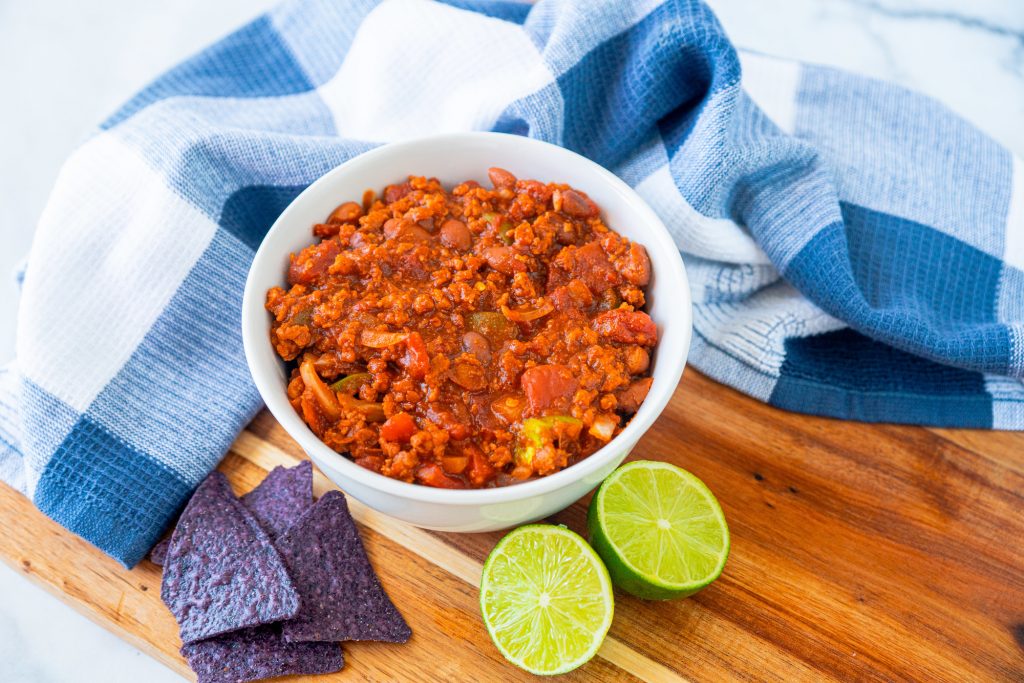 bowl of vegetarian chili with limes and dish cloth
