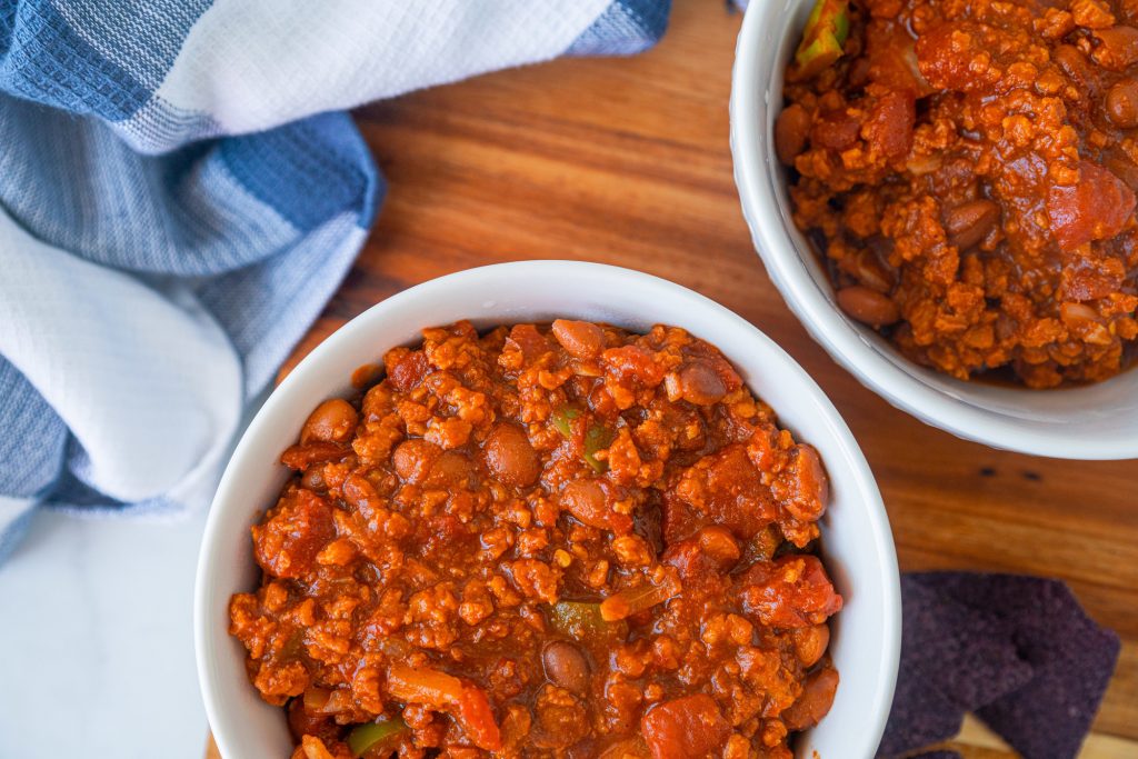 two bowls of vegan chili on brown wood