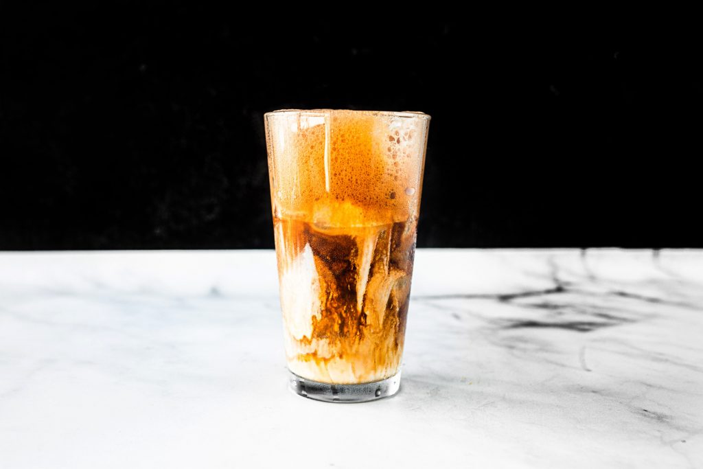 greek frappe overflowing a cup with black background and white counter