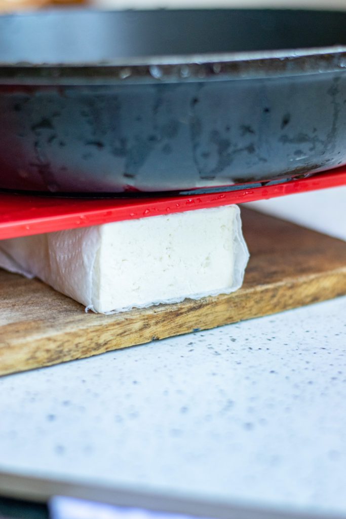 pressing out tofu under heavy pan