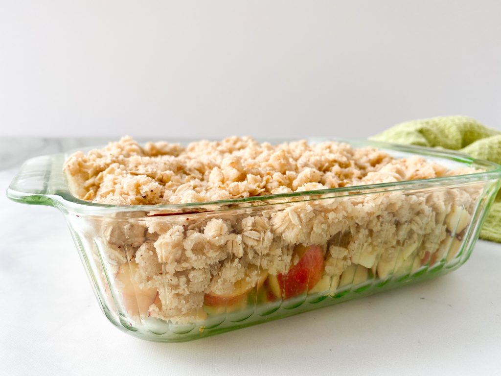 apples and oat crumble in a bowl being prepared for baking with green dish cloth in the background