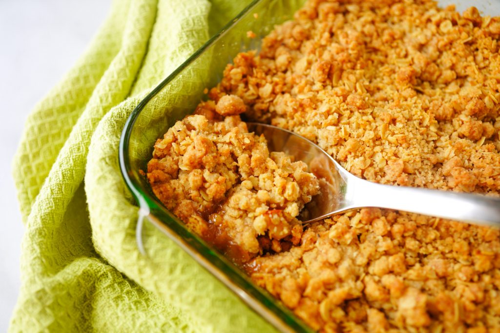 vegan apple crisp with spoon scooping out crumble