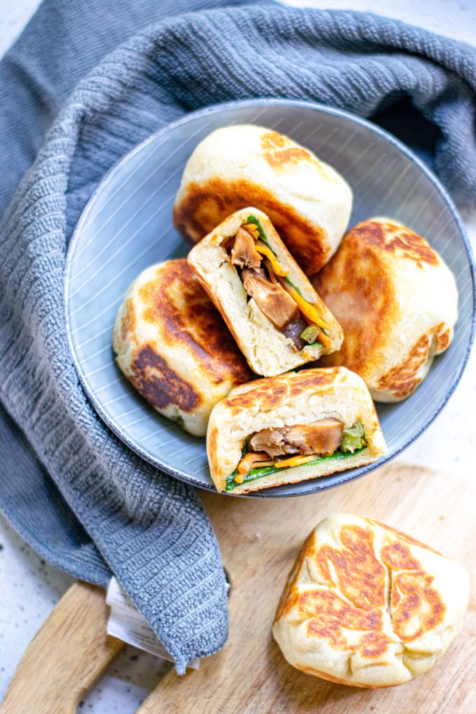 multiple vegan bao buns in a bowl with a dish towel