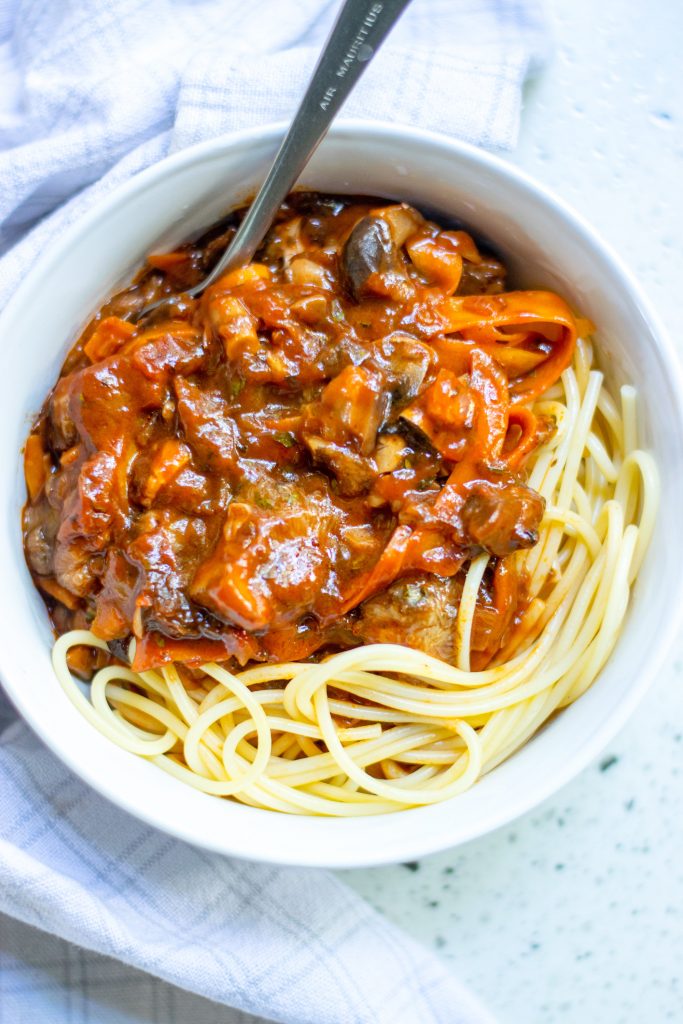 vegan bolognese sauce over pasta noodles in bowl