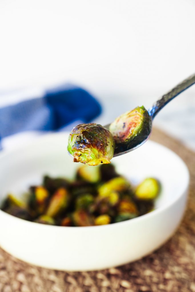 roasted brussels sprouts on fork with bowl in background