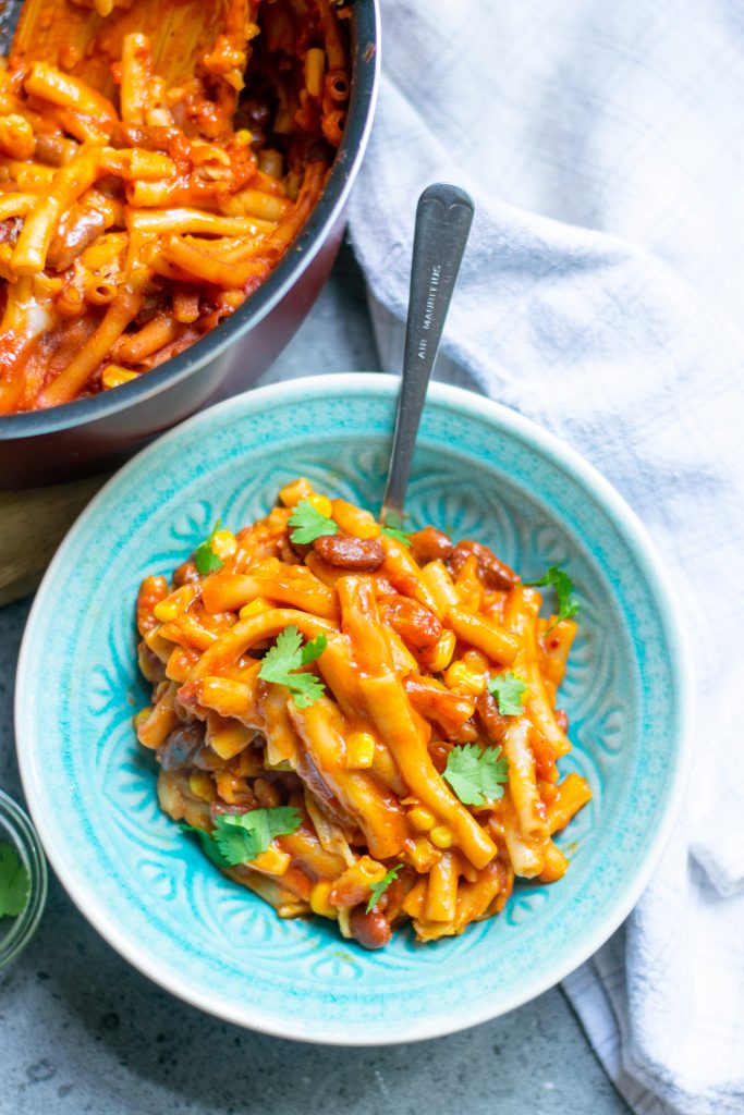 bowl of vegan chili mac with pot in the background