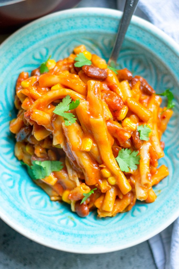 close up image of vegan chili mac with corn, beans and cilantro