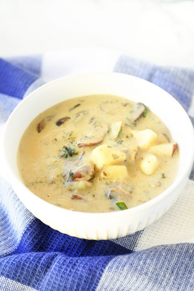 vegan clam chowder in a white bowl on a blue towel