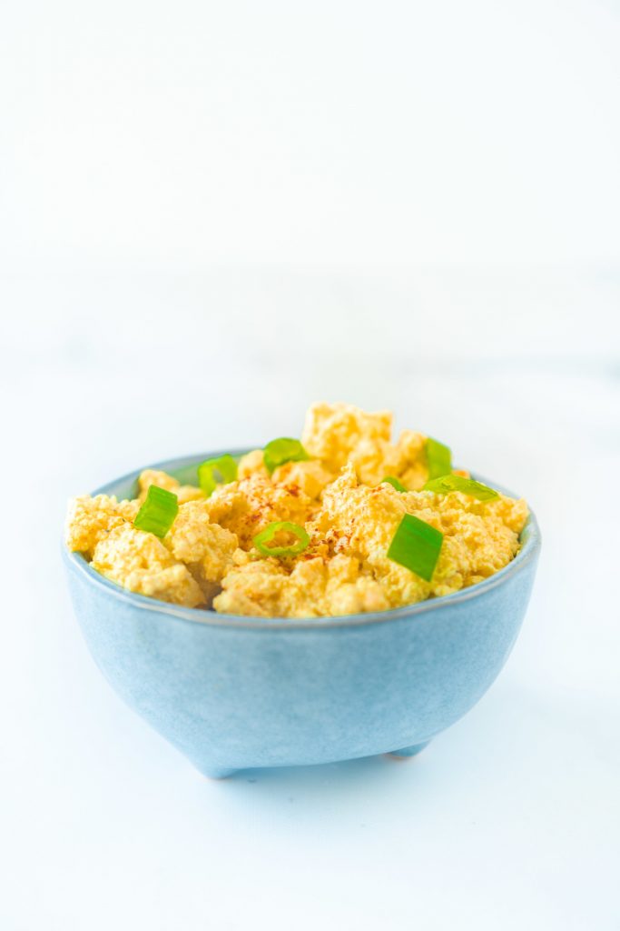 vegan egg salad with green onions in blue bowl