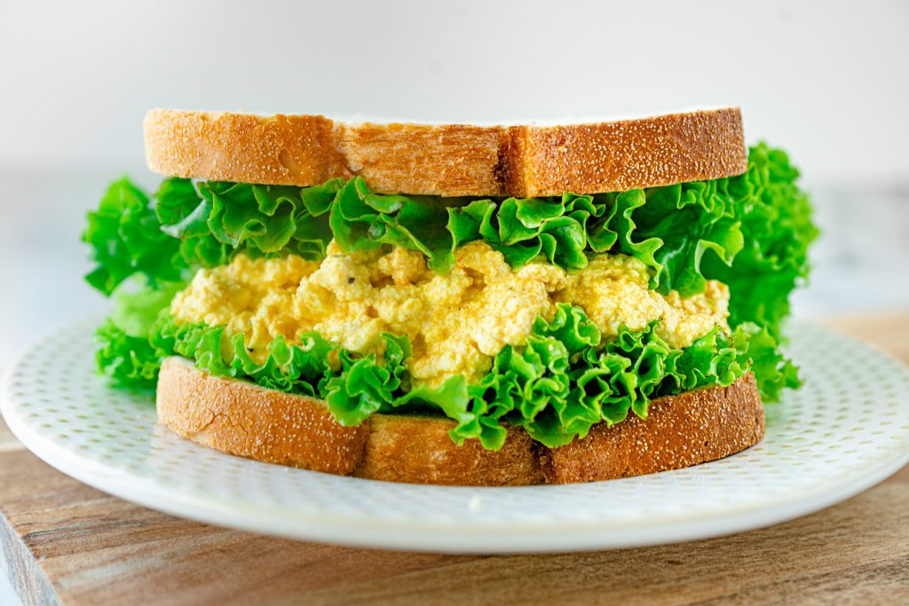 vegan egg salad sandwich on plate with lettuce