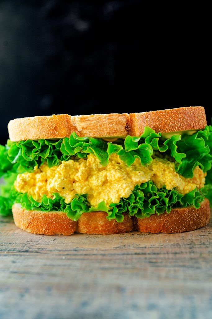 vegan egg salad sandwich on a black background