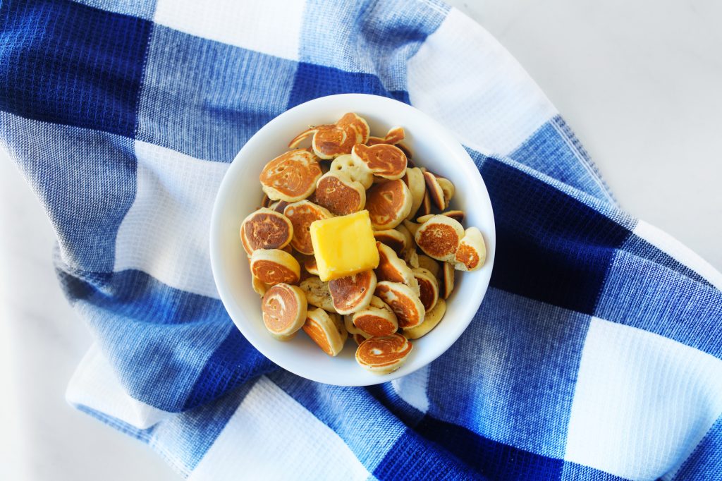 vegan pancake cereal in a bowl with blue dish towel and butter