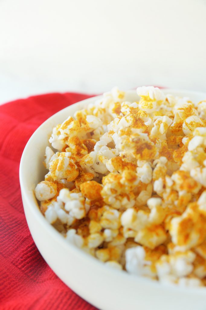 side of a bowl filled with cheesy vegan popcorn