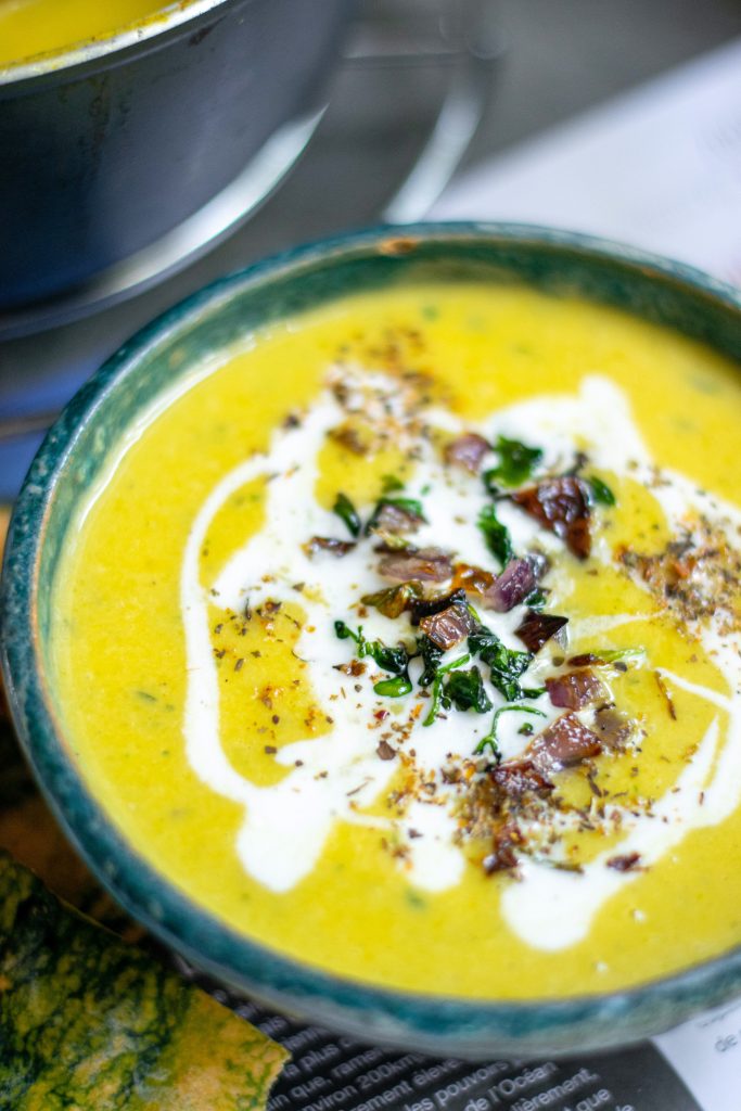 close up photo of pumpkin soup that is vegan with crispy onions topping it