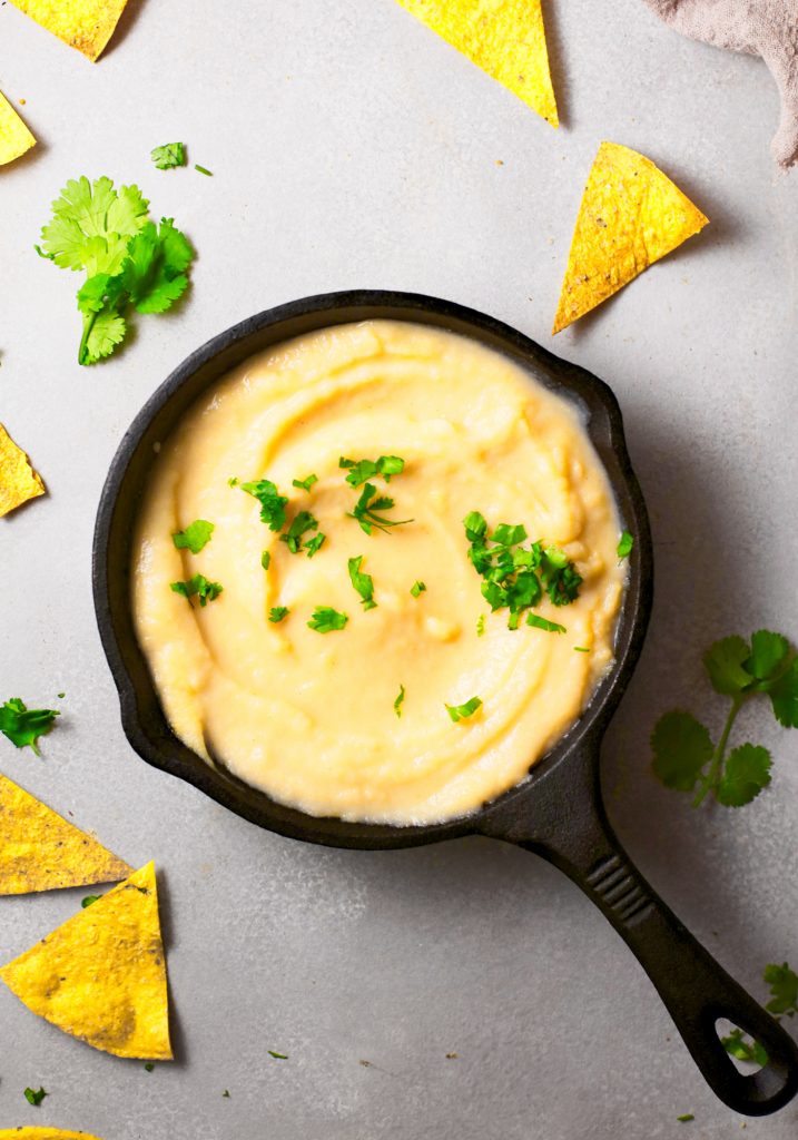 Photo of vegan queso being served in a cast iron skillet.