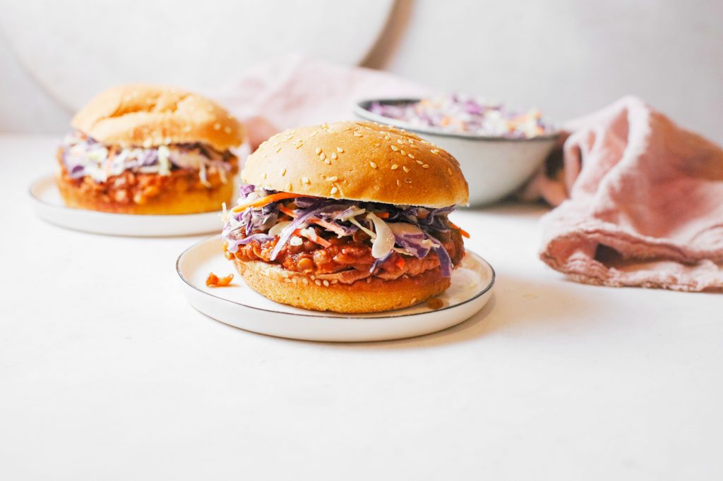two buns with vegan sloppy joes and cole slaw in the background
