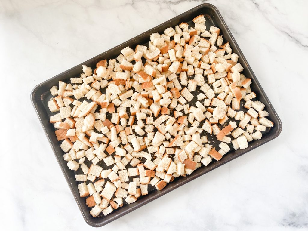 bread cubes drying on baking dish on a white countertop