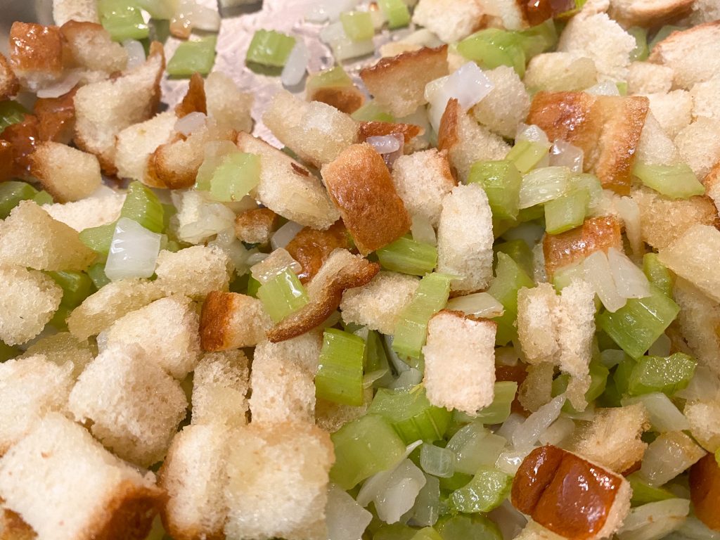 close up of bread and celery cooking in a pan on the stove 