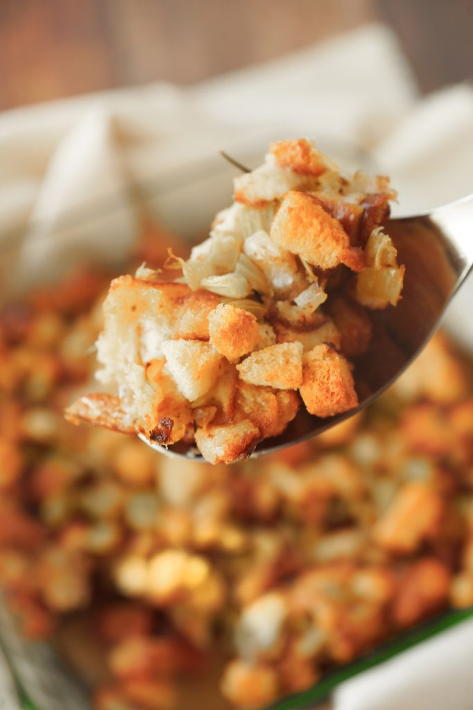 vegan Thanksgiving stuffing on a serving spoon with brown stuffing in the background
