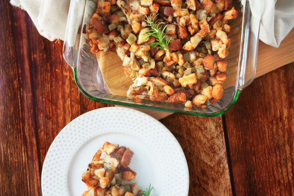 serving dish and plate with vegan stuffing in it on a brown wood background