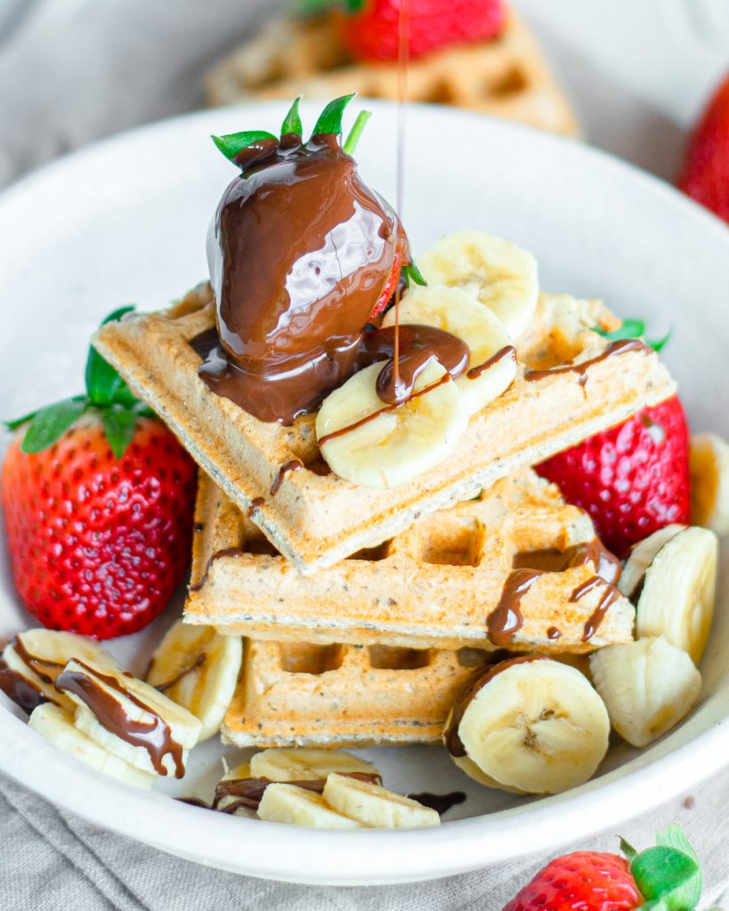 chocolate dripping onto vegan waffles with fruit