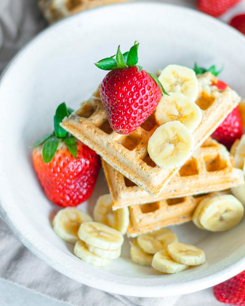 Vegan waffles on white plate with fresh fruit