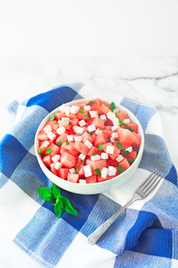 far away photo of vegan watermelon salad with fork and blue towel