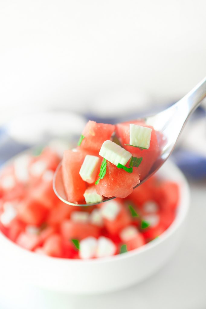 watermelon salad with vegan feta on serving spoon