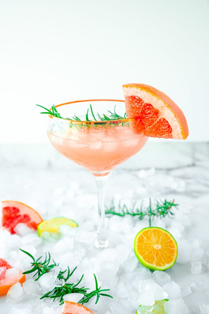 grapefruit cocktail with ice on white counter top
