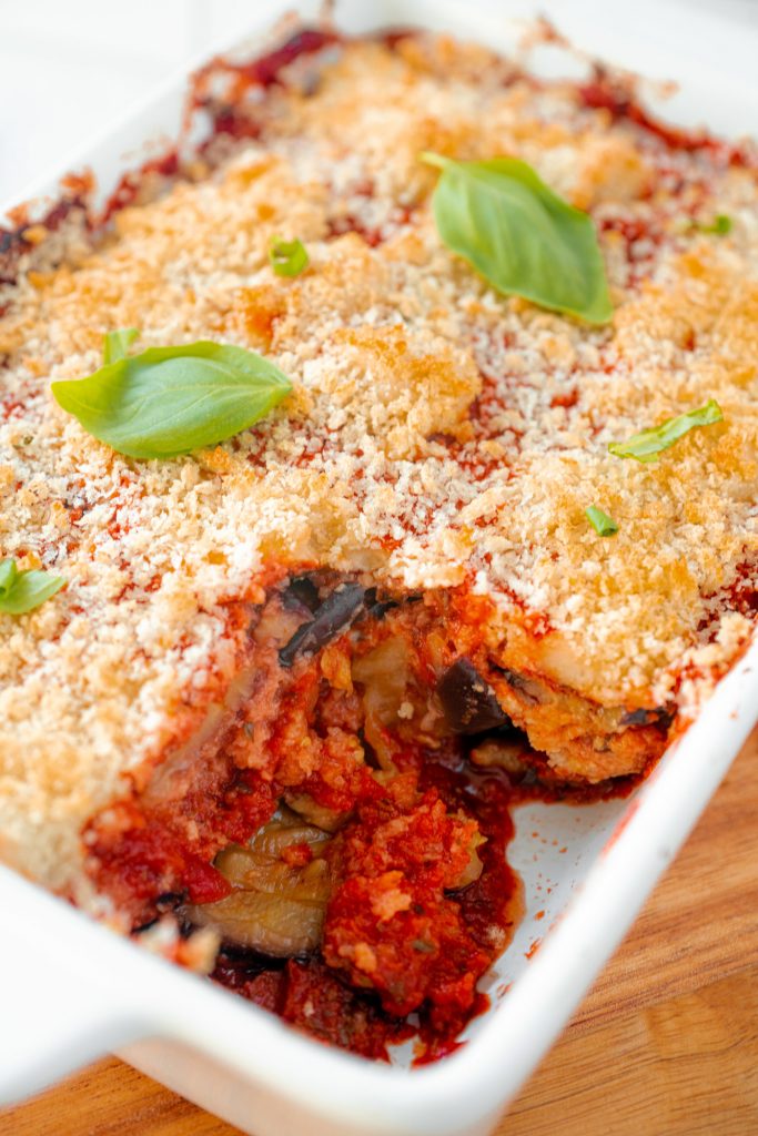 vegan eggplant parm with a slice taken out of it topped with basil