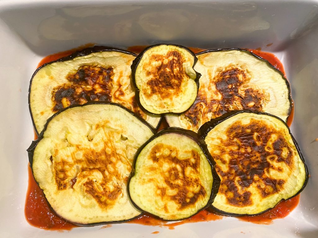 assembling an eggplant parmesan that is vegan