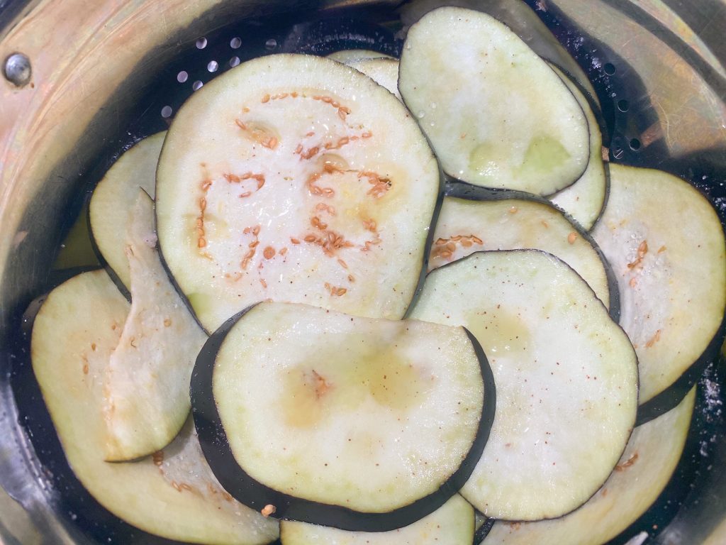 slices of eggplant sweating in a strainer