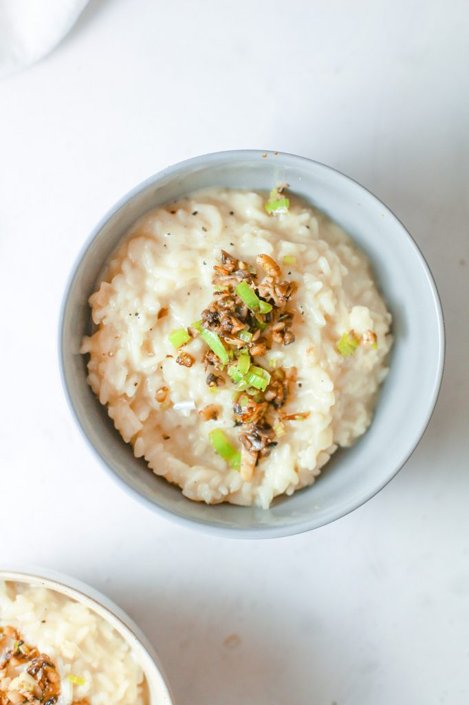 Photo of vegan mushroom risotto being served in a white round bowl.