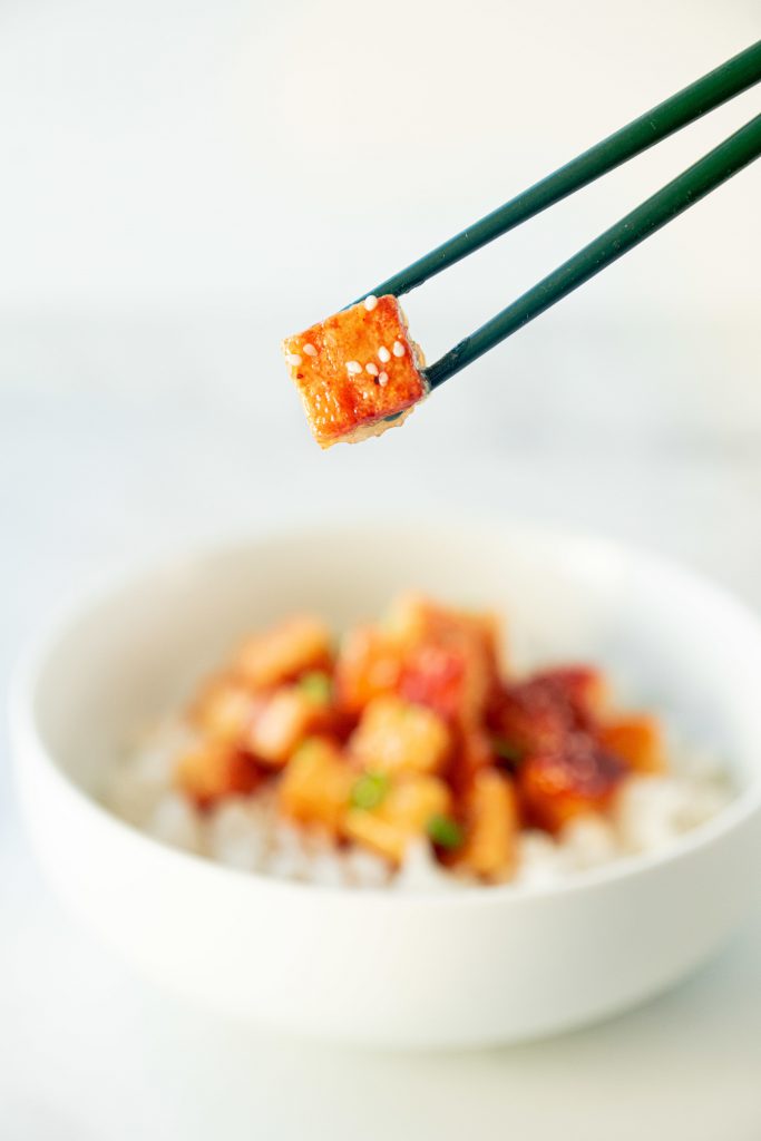 chopsticks picking up a piece of vegan orange chicken