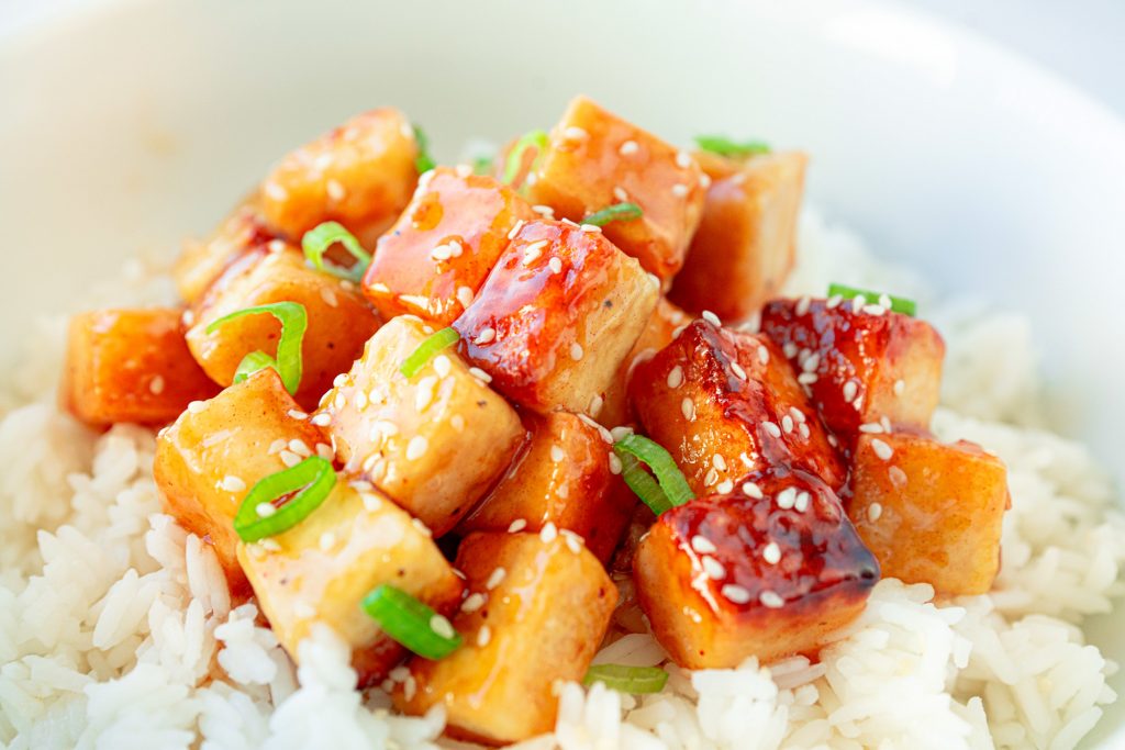 vegan orange tofu over white rice with sesame seeds