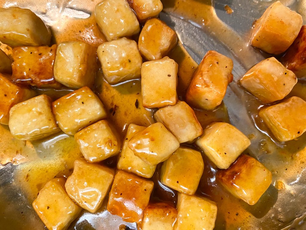vegan orange tofu tossed in orange sauce on pan