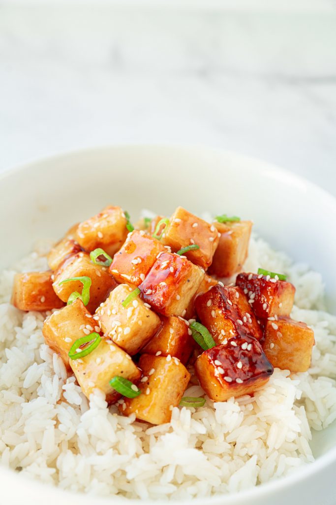 vertical image of a bowl of vegan orange chicken