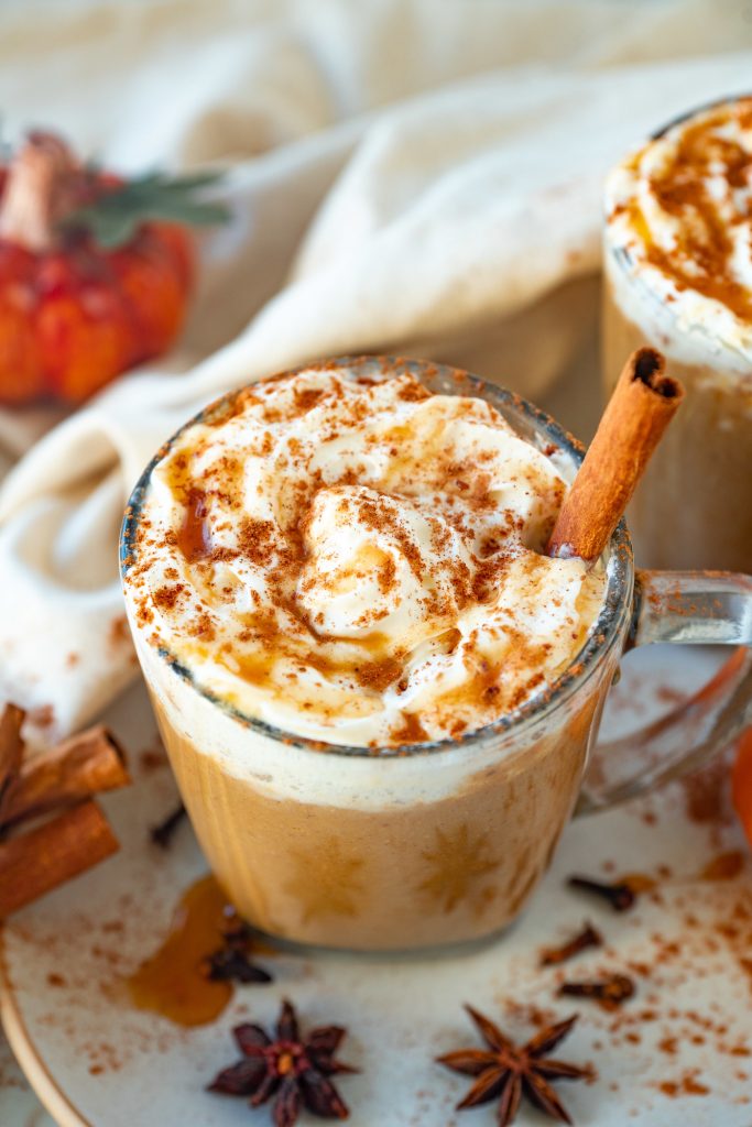 Glass mug of vegan pumpkin spice latte with a cinnamon stick, one of the best vegan fall recipes.