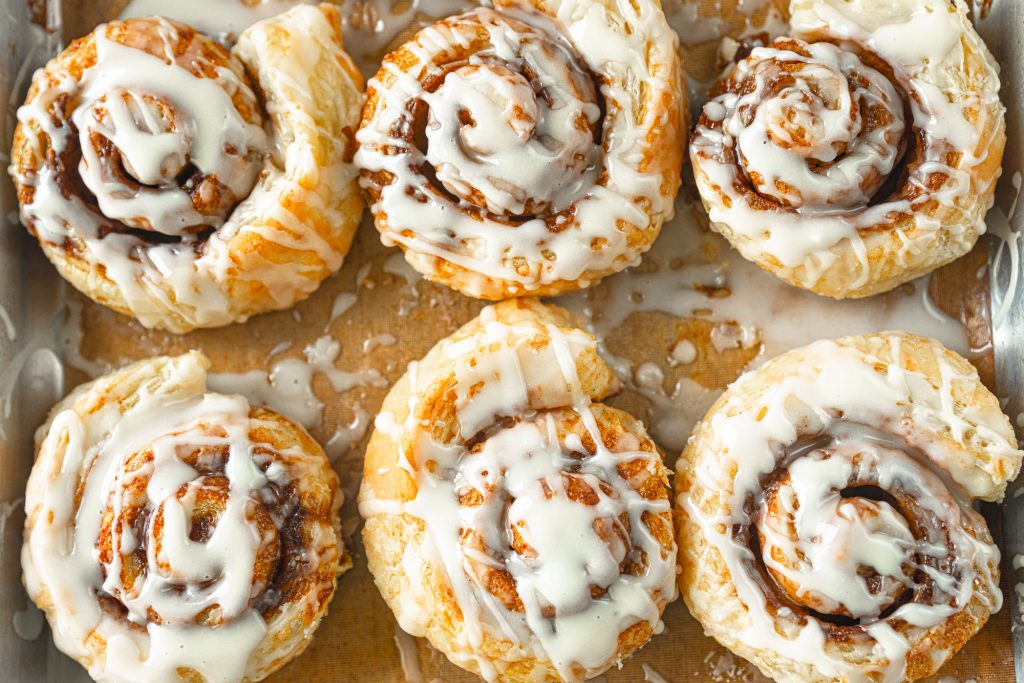 vegan puff pastry cinnamon rolls on baking sheet with glaze
