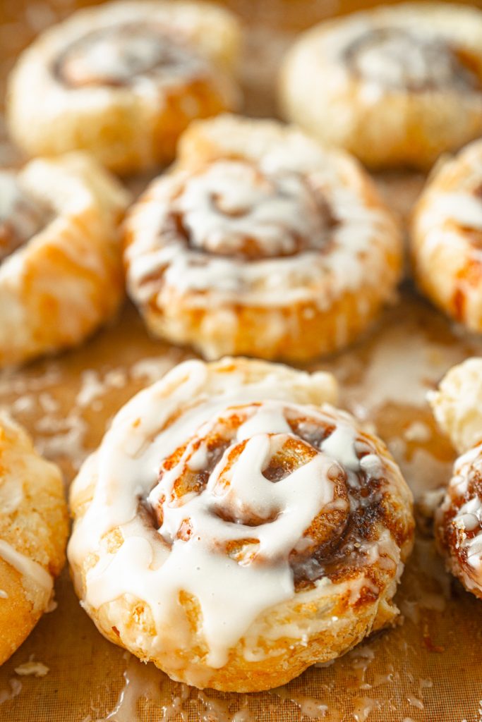 close up of sugar glaze on puff pastry cinnamon buns that are vegan