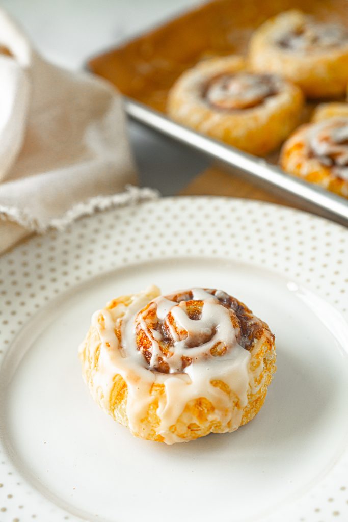 vegan cinnamon bun on a plate with pan in the background