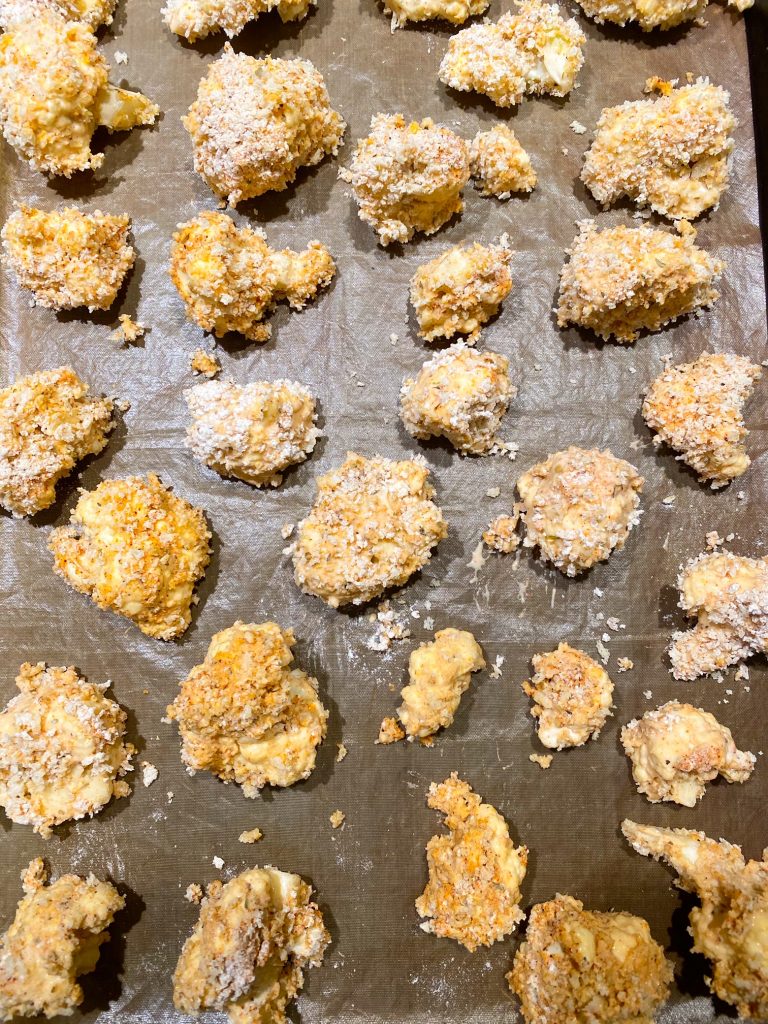 pieces of breaded cauliflower on baking tray before the oven