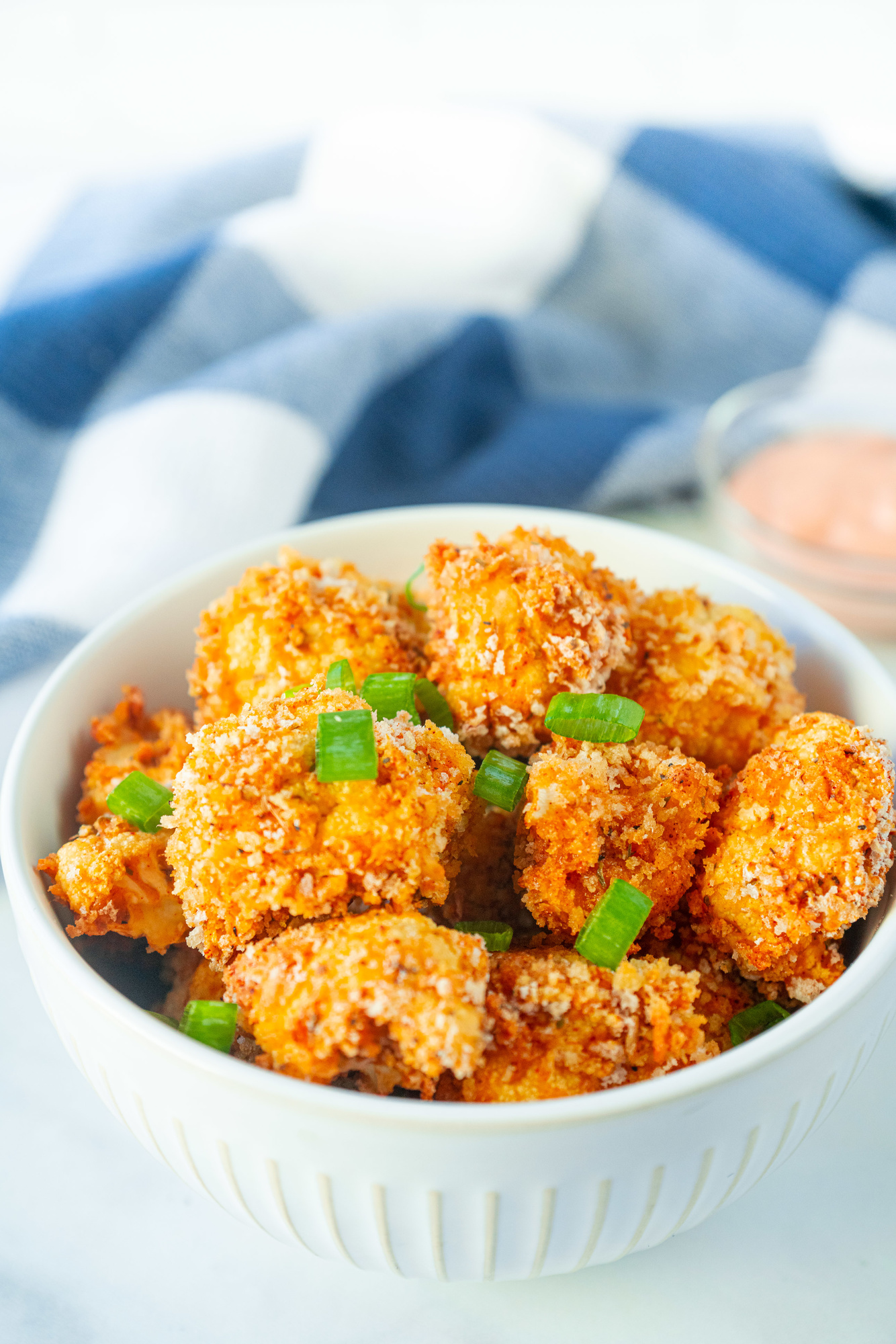 vegan crispy cauliflower bites in a bowl with green onions