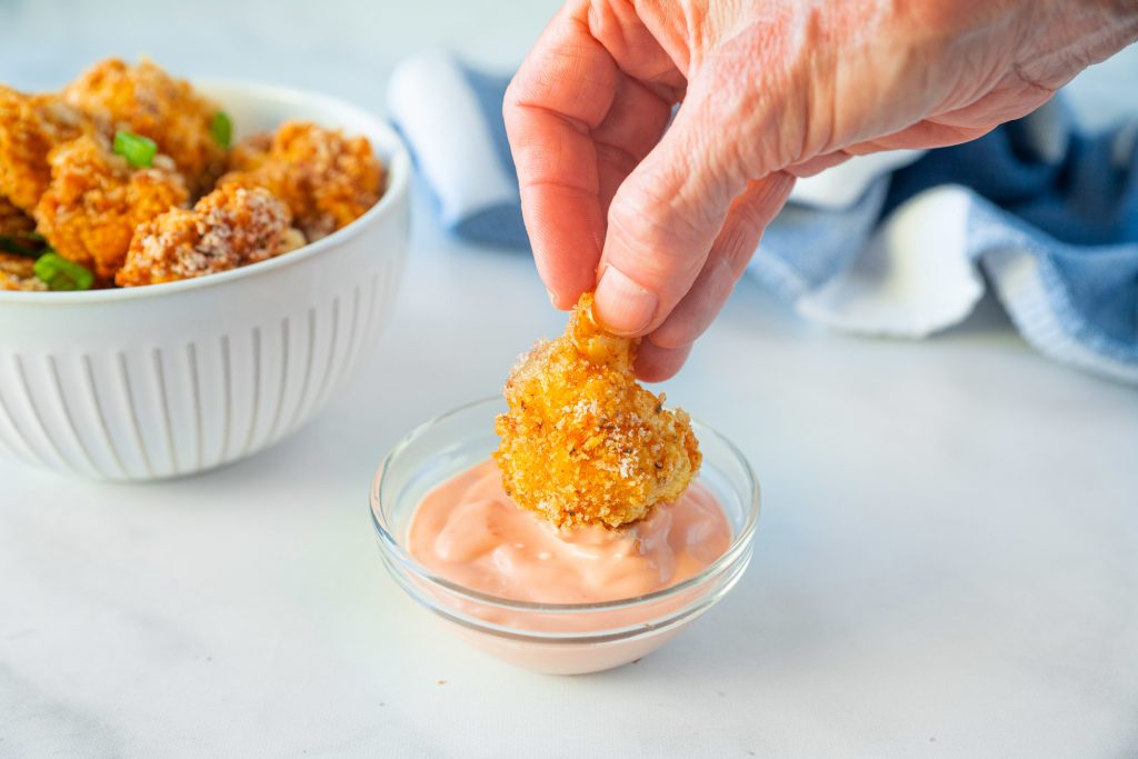 dipping panko cauliflower into vegan dipping sauce