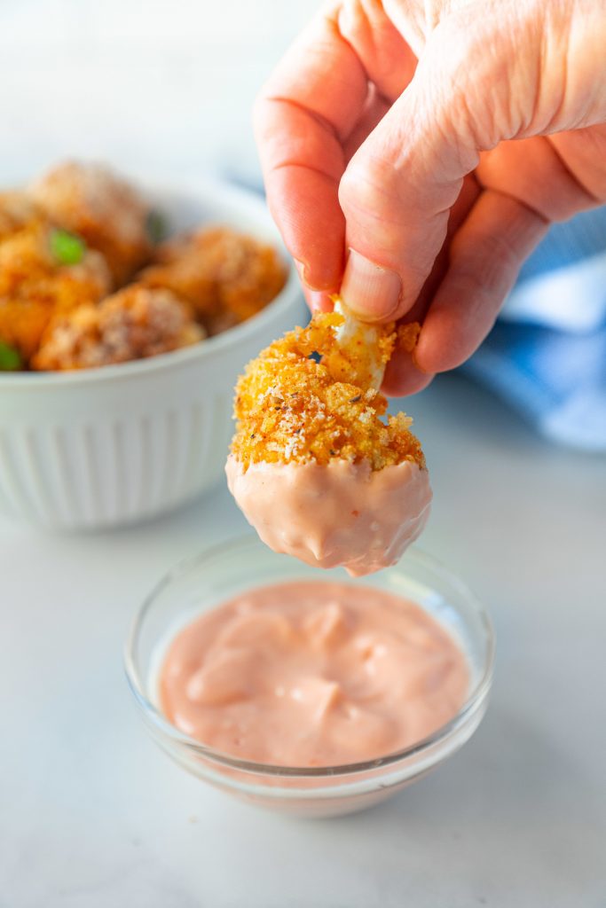crispy cauliflower nugget being dipped into sauce