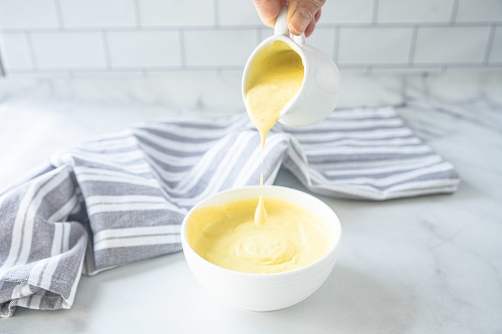 pouring vegan hollandaise sauce into a bowl