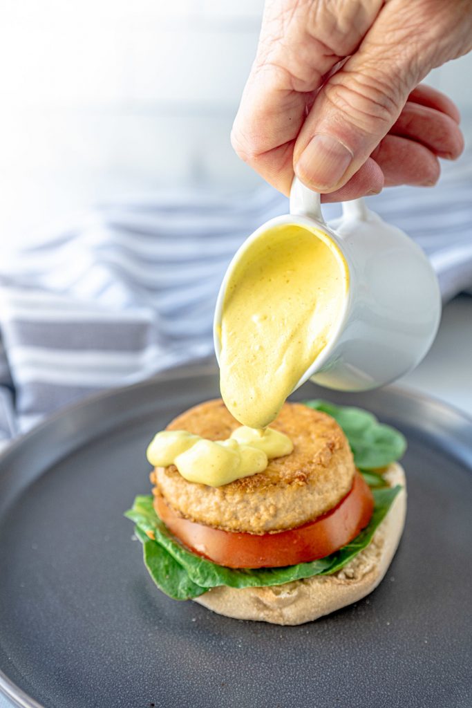 pouring vegan hollandaise sauce over vegan eggs benedict