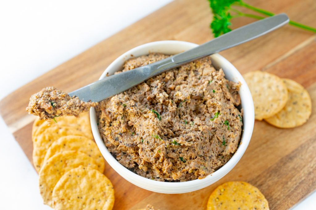 vegan mushroom pate in a bowl with a knife and crackers